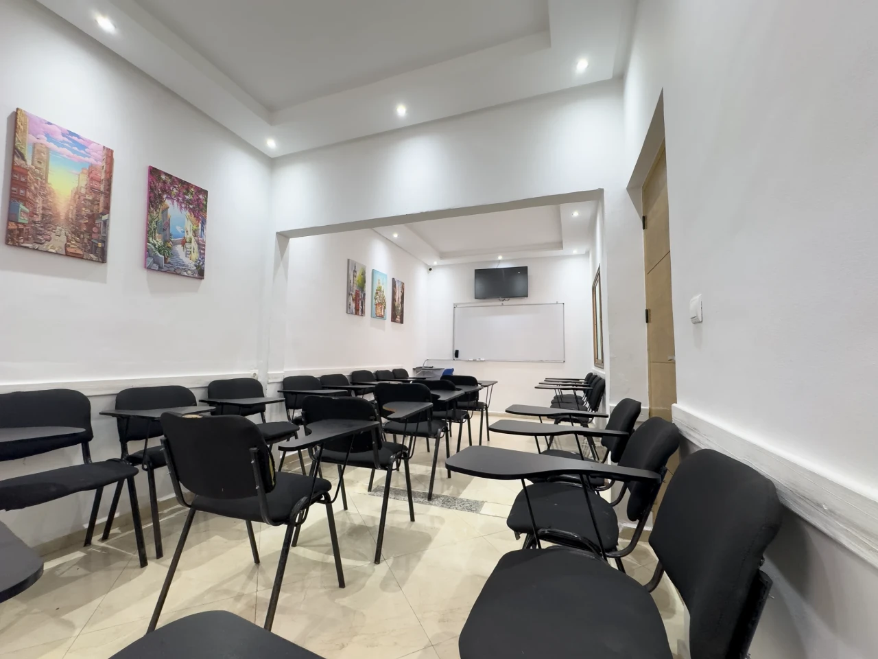 La salle de cours et ses tableaux colorés au mur.