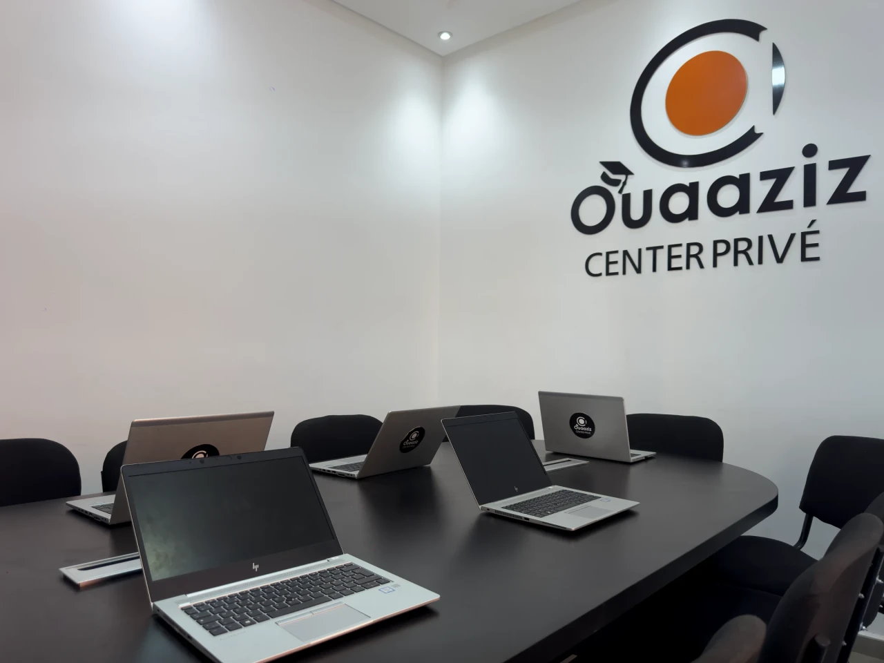 Les ordinateurs sur la table, devant le logo du centre.