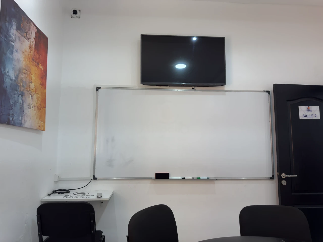 Le tableau, l’écran et les premières chaises de la salle.