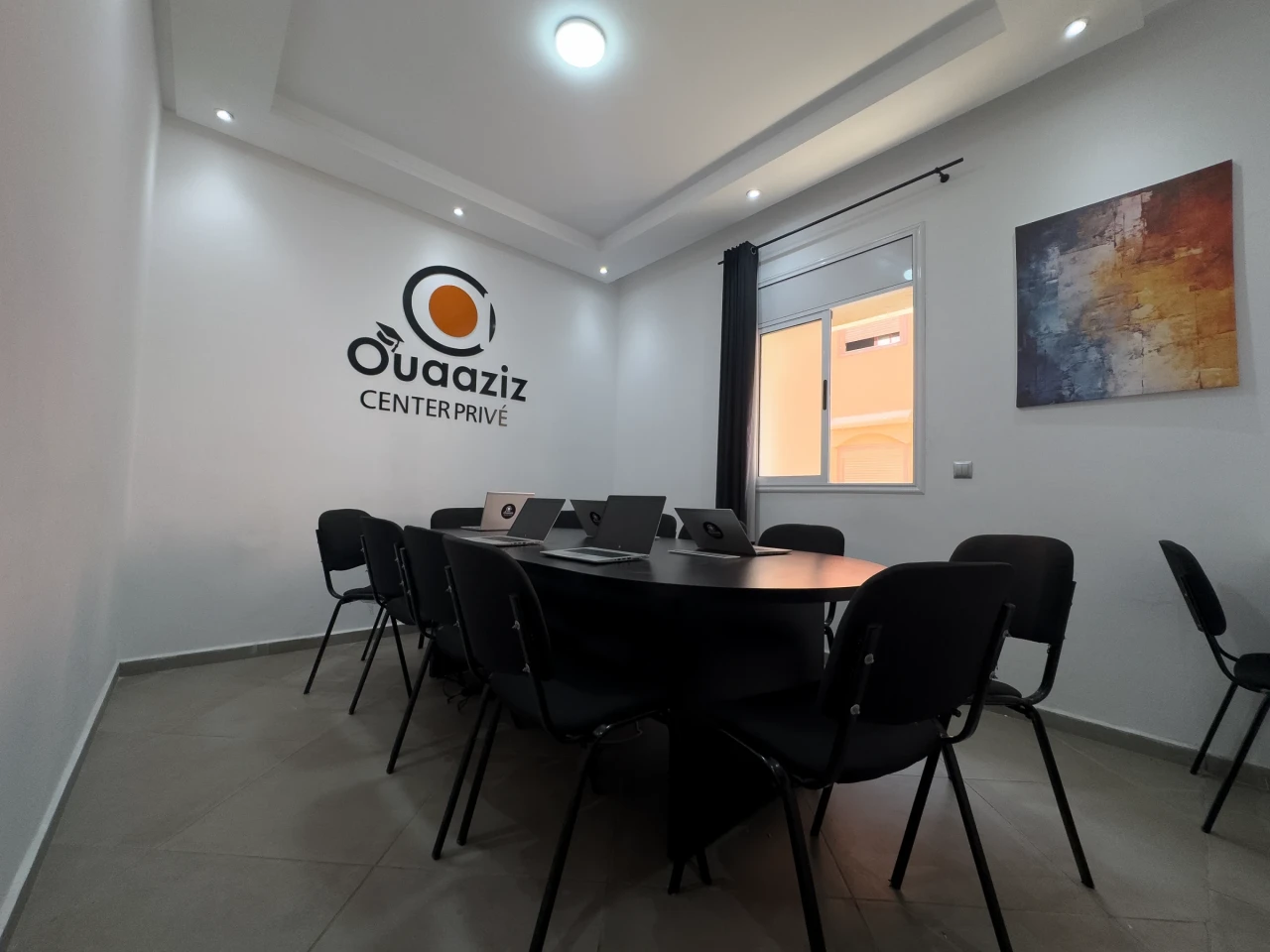 La salle avec sa table ovale et ses ordinateurs.
